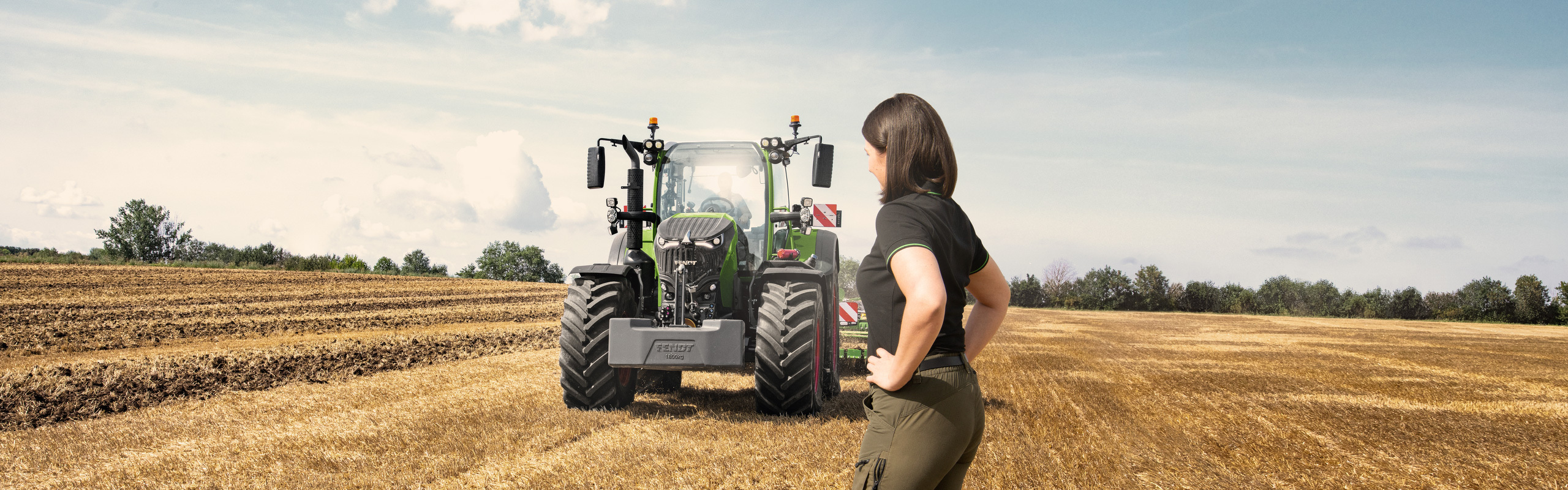 A farmer stands in the field in front of her new Fend 700 Vario Gen7.