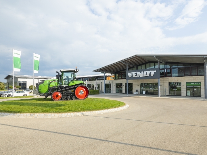 A Fendt 1100 Vario MT tracked tractor on a traffic circle in front of the Fendt Forum Visitors Center