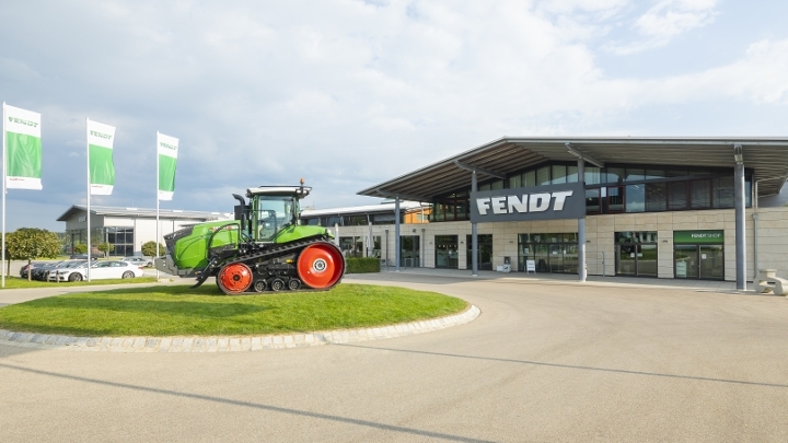 A Fendt 1100 Vario MT tracked tractor on a traffic circle in front of the Fendt Forum Visitors Center