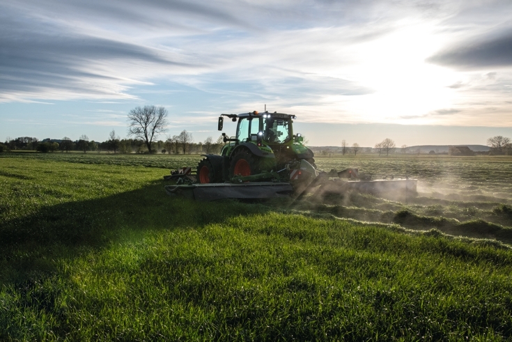 Fendt tractor with slicer mower working in a green field