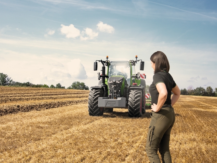 A farmer standing on a stubble field in front of her Fendt 700 Vario Gen7.