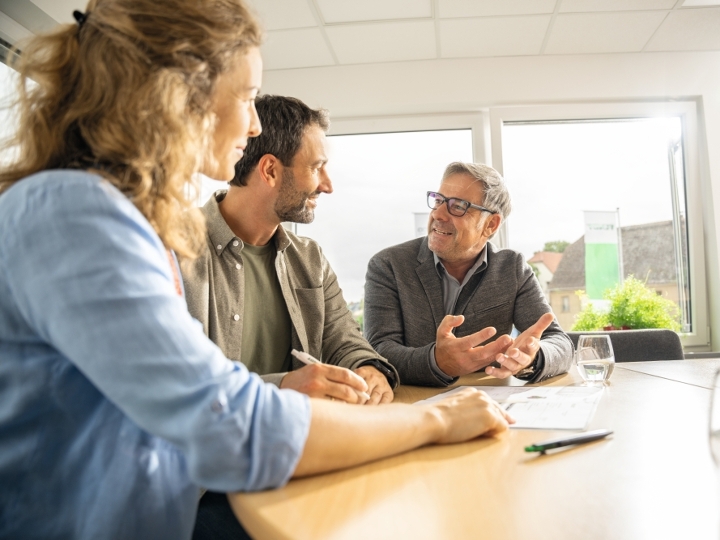 A female and male farmer sitting in the office with their Fendt dealer and receiving advice