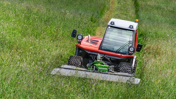Fendt Slicer Alpine A green Fendt Slicer Alpine mowing a green meadow, leaving a trail of freshly cut grass.