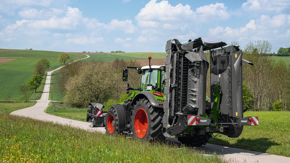 Transport position A green Fendt Vario Tractor on the field path with transport position of the mowers.