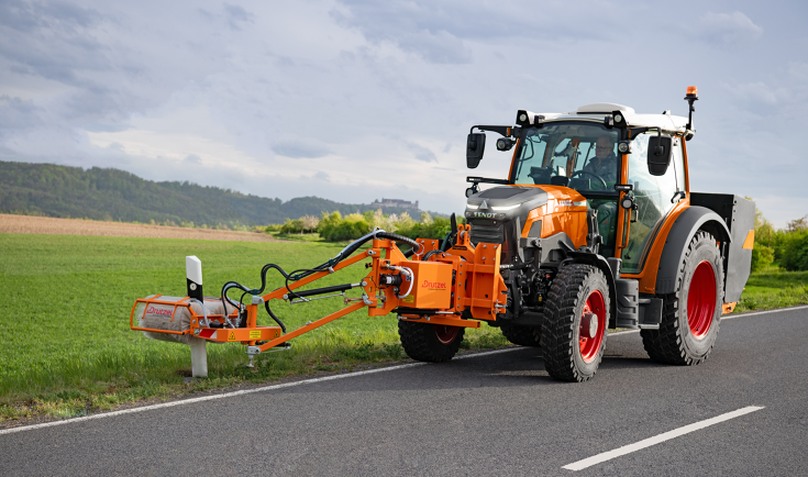 A Fendt e107 Vario cleaning reflector posts A Fendt e107 Vario in municipal orange with a front-mounted brush for cleaning guiding posts is driving along the road and cleaning the reflector posts.