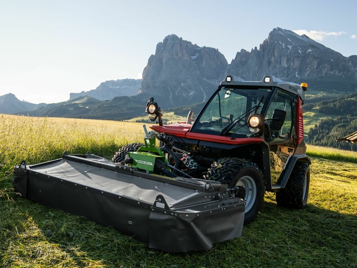 Fendt Slicer Alpine The Fendt Slicer Alpine mower in action on a mountain meadow with mountains and blue sky in the background