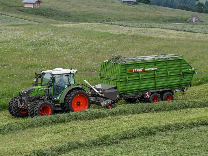 Fendt Tigo ST A green Fendt tractor with red rims and a green Fendt Tigo forage wagon with red rims driving on a green mountain meadow
