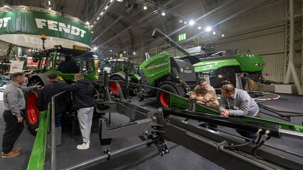 Trade fair visitors at the Fendt stand in Finland Trade fair visitors leaning on a Fendt rake, with a round baler and a Fendt combine harvester in the background