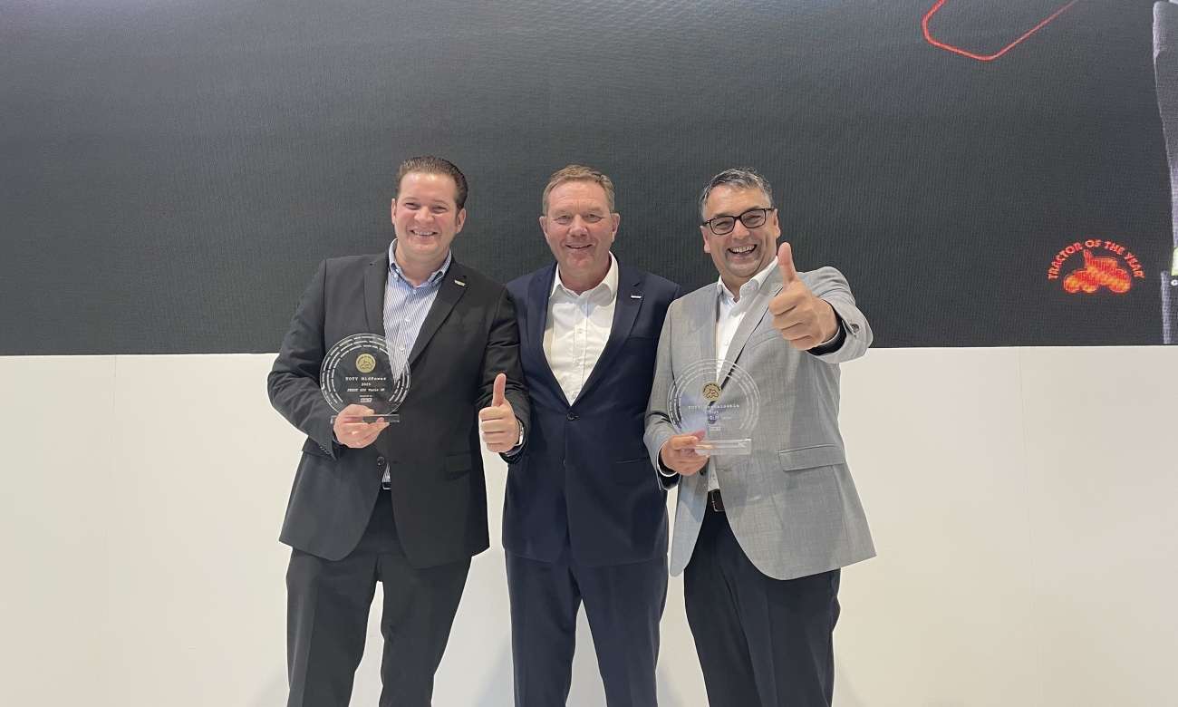 Three men stand on a stage and cheer about winning two TotY 2025 awards.