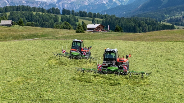 Fendt Twister Alpine tedder Two Fendt Twister Alpine tedders in action on a green mountain meadow. In the background are two huts and a forest