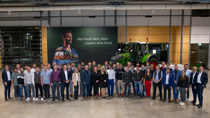 Fendt employees with 10 years of service together with the Fendt management in front of a Fendt tractor