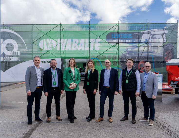 Georg Herbig (Sales Director Fendt Central and Eastern Europe | left) together with sales partner Ivabalté in Lithuania at the trade fair 7 people, women in the centre, a woman with a green jacket holds a prize in her hand, in front of an Ivabalté logo