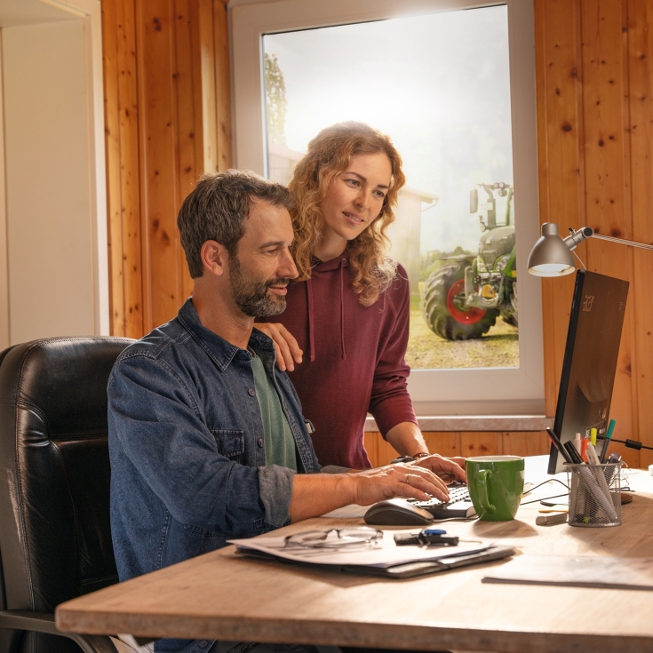 A farmer couple in front of their office computer, creating field boundaries with FendtONE Agronomy.