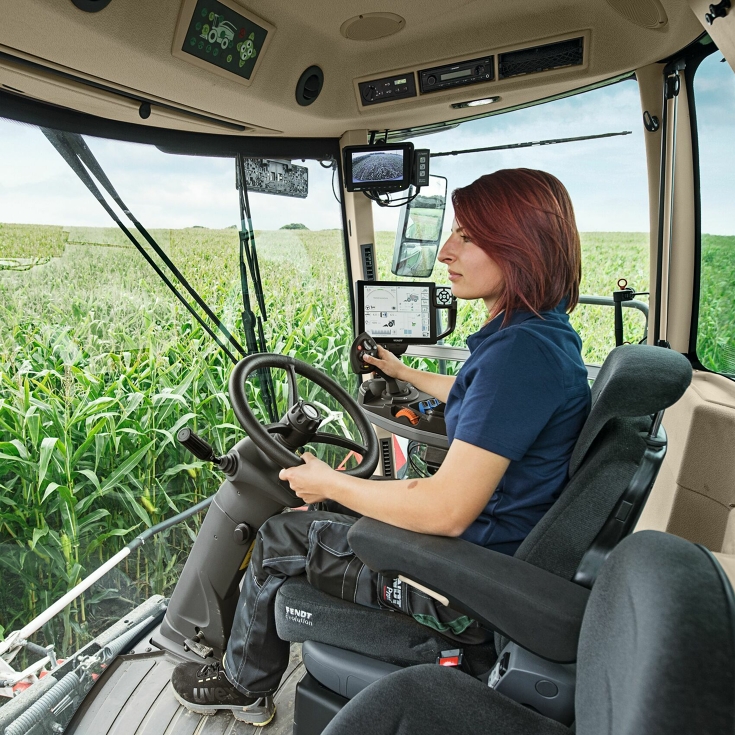 A farmer sits in her Fendt Katana and steers the machine through a maize field.