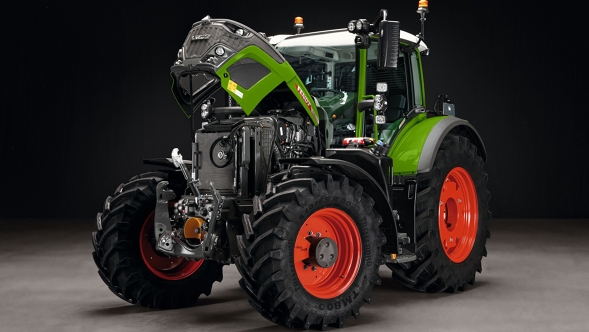The green Fendt 600 Vario with red rims standing with its bonnet open on a grey floor. The background is black.