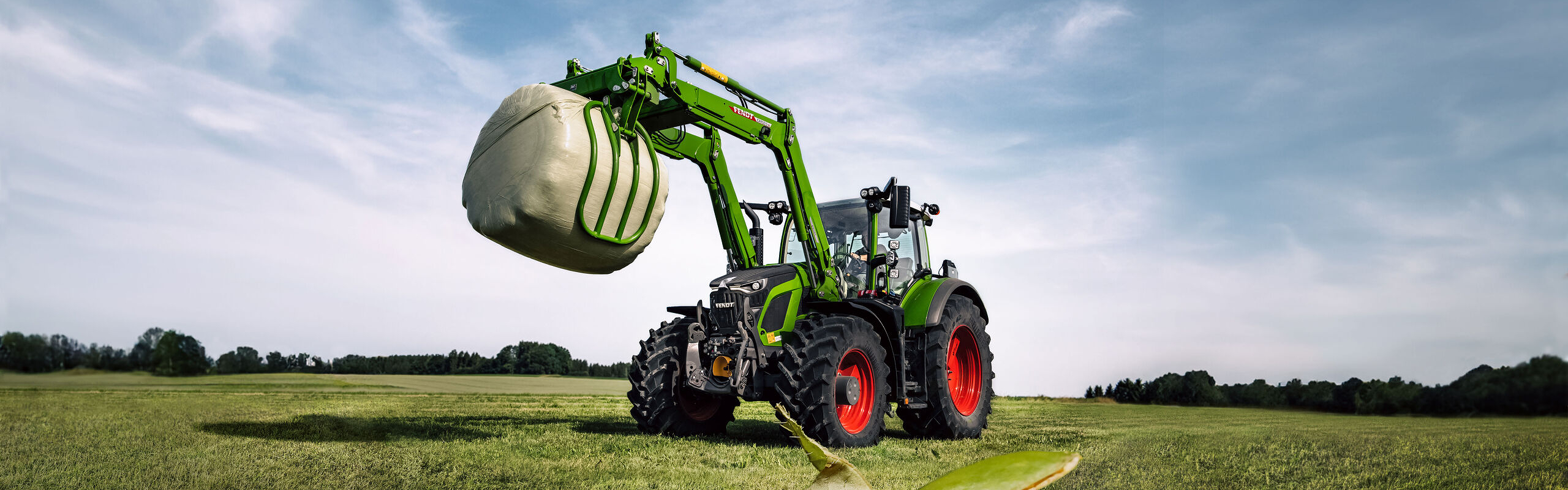 Fendt 600 Vario with front loader in a field with ants in the foreground