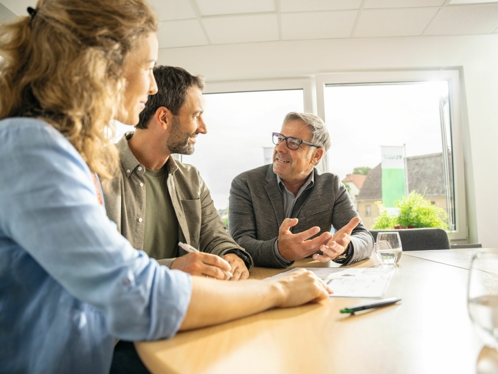 Male and female farmers sitting at a table with a Fendt dealer and getting advice.