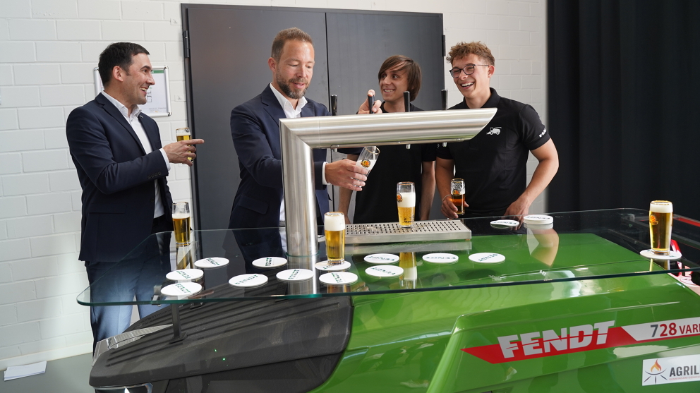 Four men, two of whom are apprentices (right), stand behind the drinks dispenser and laugh while one of them pours himself a cold drink