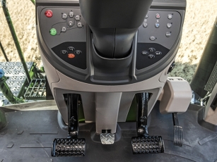 Interior view of the cab of the Fendt 900 Vario MT with central control block and two black foot pedals on a grey floor for adjusting the steering column
