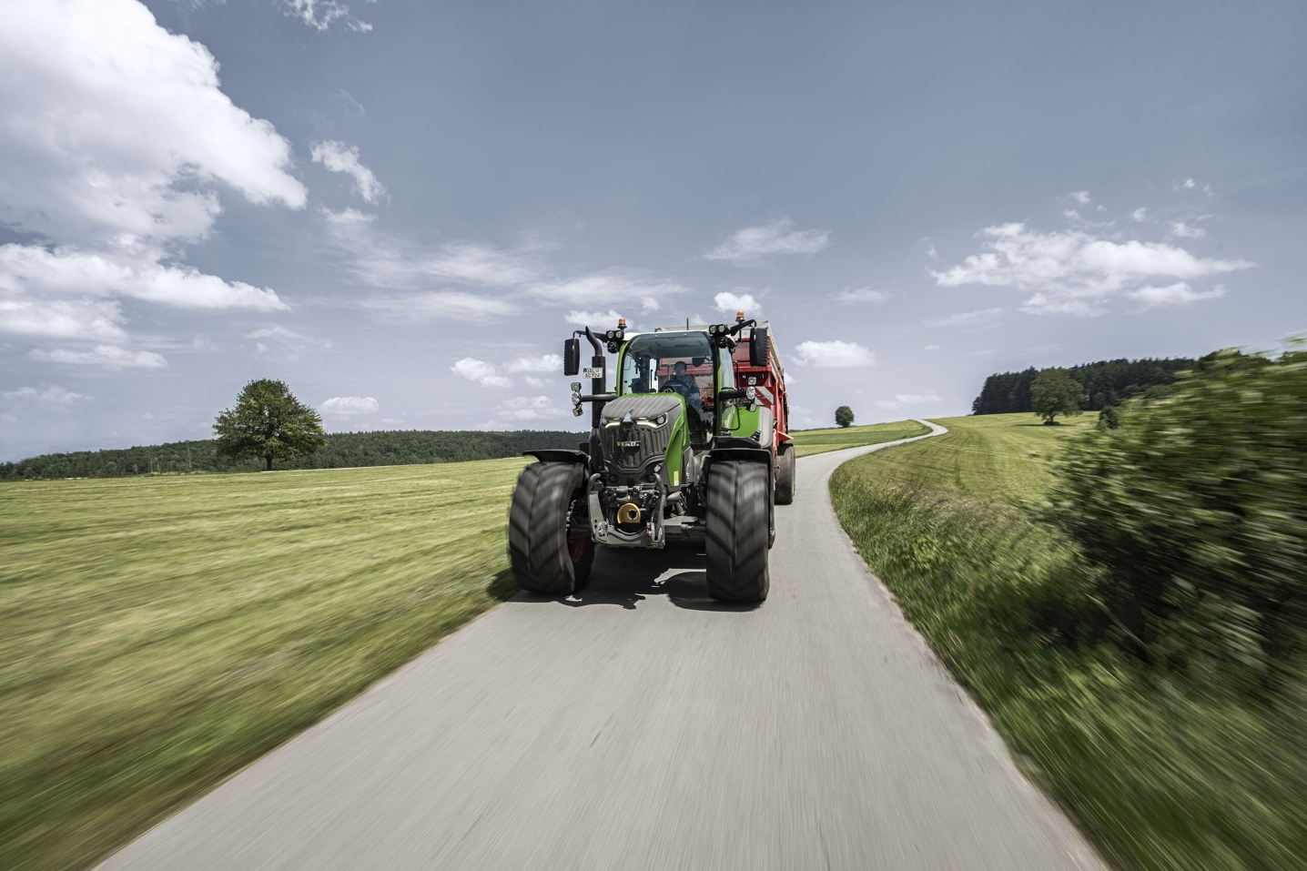 A Fendt 700 Vario with attached forage wagon on a country road in the summer