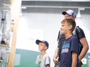 "Two children and an adult looking at a display case with models in the Fendt brand world, surrounded by wall texts and pictures relating to the company's history