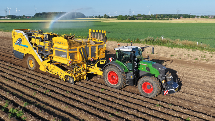 A green Fendt tractor driving a yellow Keiler II RK22 potato harvester from ROPA over a field and harvesting potatoes.