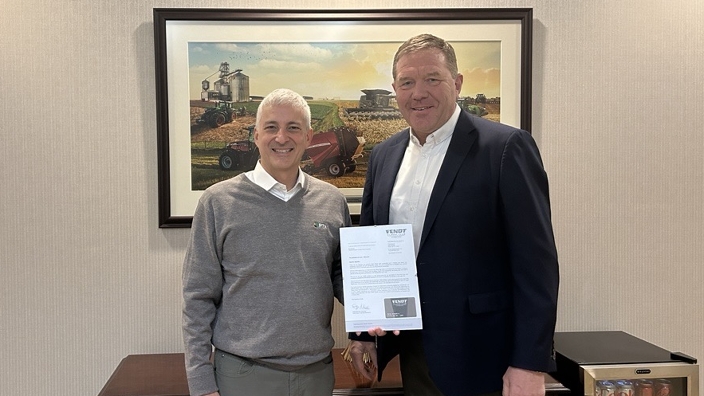 Two men standing in an office, one holding a document.