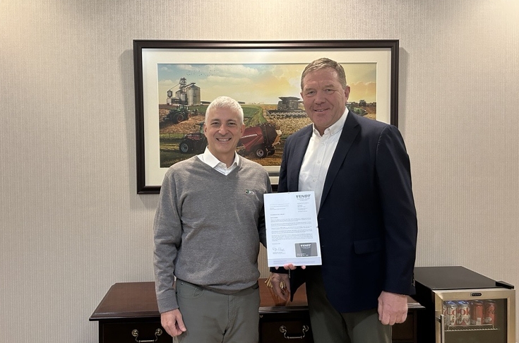 Two men standing in an office, one holding a document.