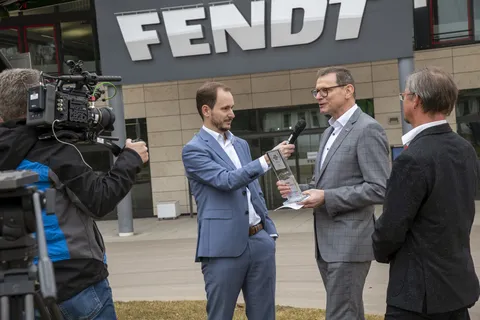 Una troupe televisiva con microfoni e telecamere intervista Walter Wagner davanti al Fendt Forum.