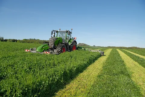un Fendt 724 Vario Gen7.1 verde falcia con una falciatrice anteriore e posteriore Fendt Slicer su un prato.
