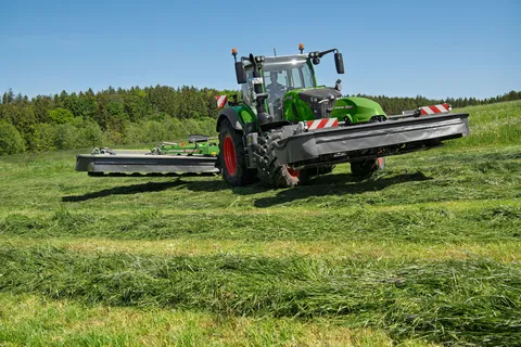 Un Fendt 724 Vario Gen7.1 verde in manovra con falciatrici anteriori e posteriori Fendt Slicer sollevate su un prato.