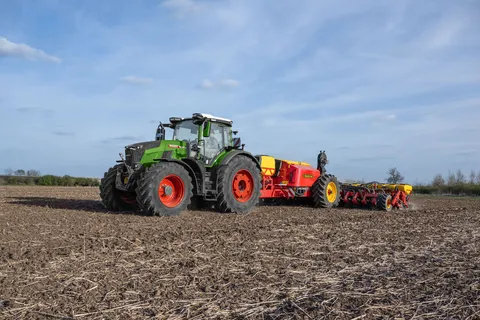un Fendt 800 Vario verde lavora con una seminatrice rossa di Väderstad su un campo.