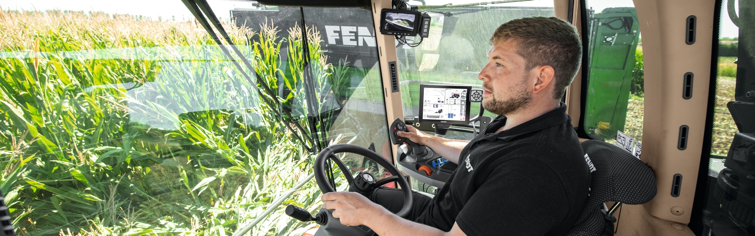 Un agricoltore siede nella cabina conducente della Fendt Katana in un campo di mais