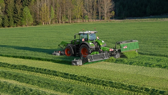 Fendt Slicer Un trattore Fendt Vario verde con cerchioni rossi sul campo con falciatrici.
