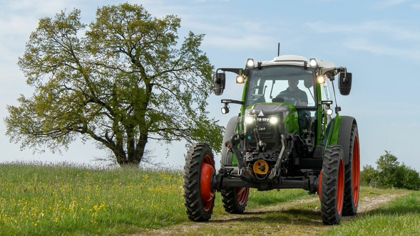 Il Fendt e100 Vario trattore standard Un Fendt e100 V Vario verde procede su un sentiero in primavera