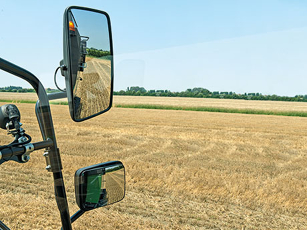 Specchio retrovisore Fendt Serie L Primo piano dei grandi specchietti retrovisori regolabili elettricamente e riscaldati di una mietitrebbia Fendt serie L con una vista del campo circostante sullo sfondo