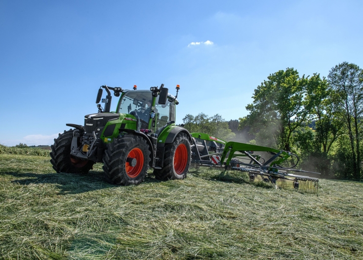 Un Fendt 500 Vario verde con un ranghinatore ad andanatura centrale Fendt Former attraversa un prato falciato ed esegue una ranghinatura.