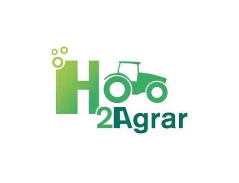 H2-Agrar logotipe pavaizduotas didelis raidė „H“, kurios kairysis kraštas sudarytas iš mažų burbuliukų, skrendančių į dešinę, o dešinėje pusėje – traktorius ir užrašas „2Agrar“. Viskas pavaizduota spalvų skalėje nuo šviesiai žalios iki tamsiai žalios.