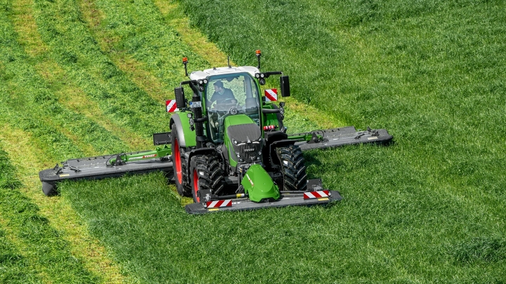 Žalioje pievoje žaliu padargu „Fendt Slicer“ šienauja žaliasis traktorius „Fendt 600 Vario“, fone matyti šienavimo pėdsakai.