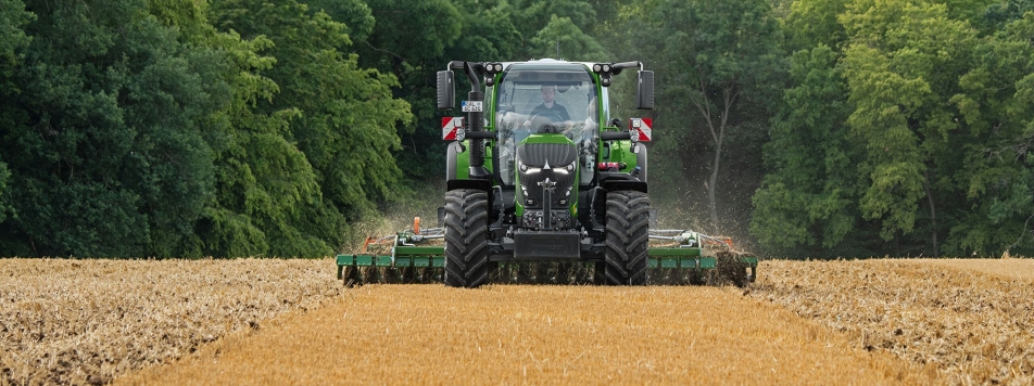 „Fendt 620 Vario“ Lauke žemę įdirbantis „Fendt 620 Vario“, fone – miškas