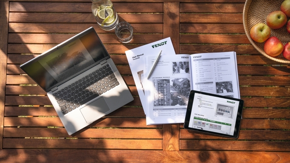 Fendt Online reserveonderdelencatalogus De online onderdelencatalogus staat open op een laptop en er liggen meerdere handleidingen op tafel.