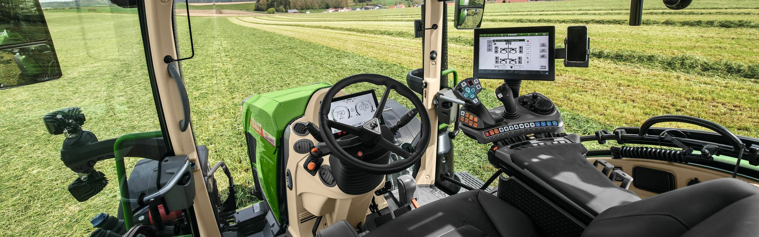 Binnenaanzicht van de cabine van de Fendt 600 Vario met uitzicht over een groene weide.