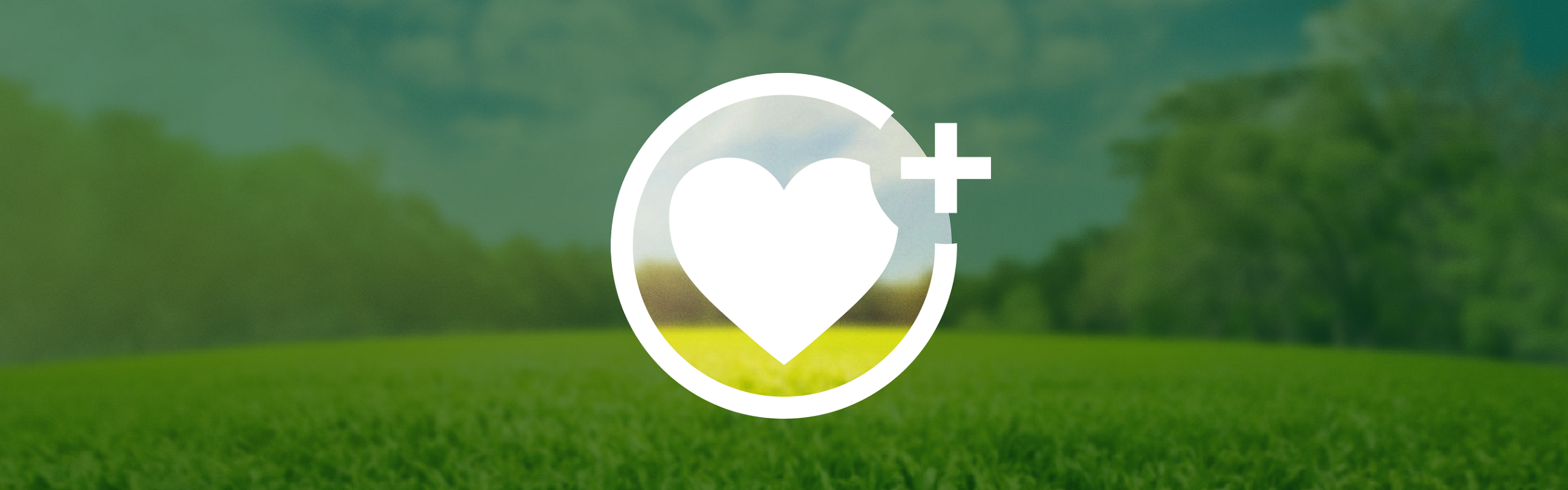 Een wit hart bevindt zich in een cirkel, waarin een plus aan de rechterkant staat. De achtergrond laat een groene bosweide onder een blauwe hemel zien, die buiten de cirkel door een donkergroene, deels transparante laag wordt verduisterd.