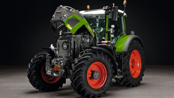 De groene Fendt 600 Vario met rode velgen staat met open motorkap op een grijze grond. De achtergrond is zwart.