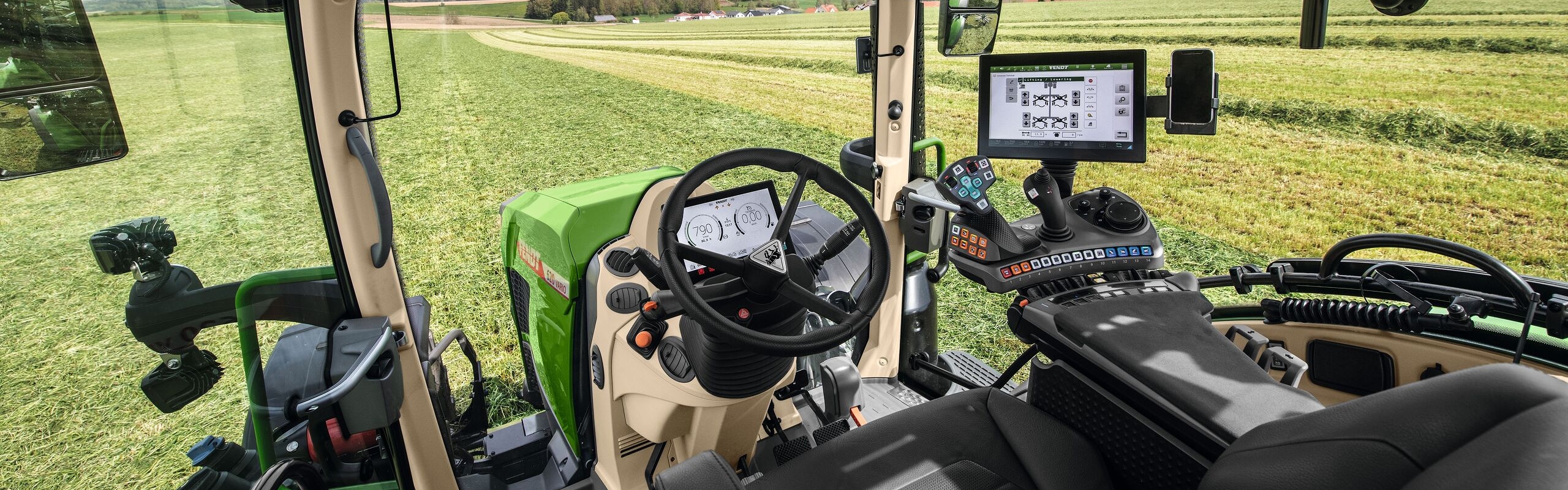 Binnenaanzicht van de cabine van de Fendt 600 Vario met uitzicht over een groene weide.