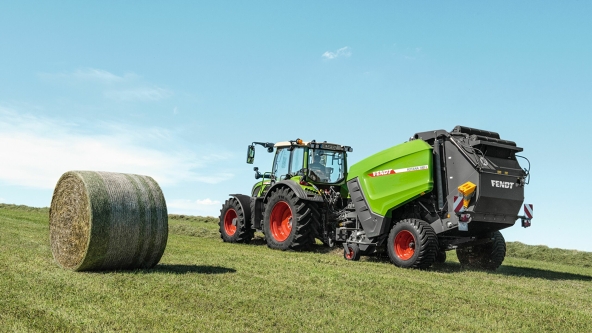 Een Fendt-tractor met een Fendt Rotana-rondebalenpers tijdens het balenpersen op het veld