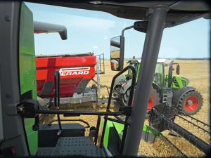 Bewaking van de afvoerpijp van de Fendt L-Series zicht vanuit de cabine van een Fendt L-Series maaidorser op de afvoerpijp tijdens het snel lossen van het gewas in een rood overlaadvoertuig