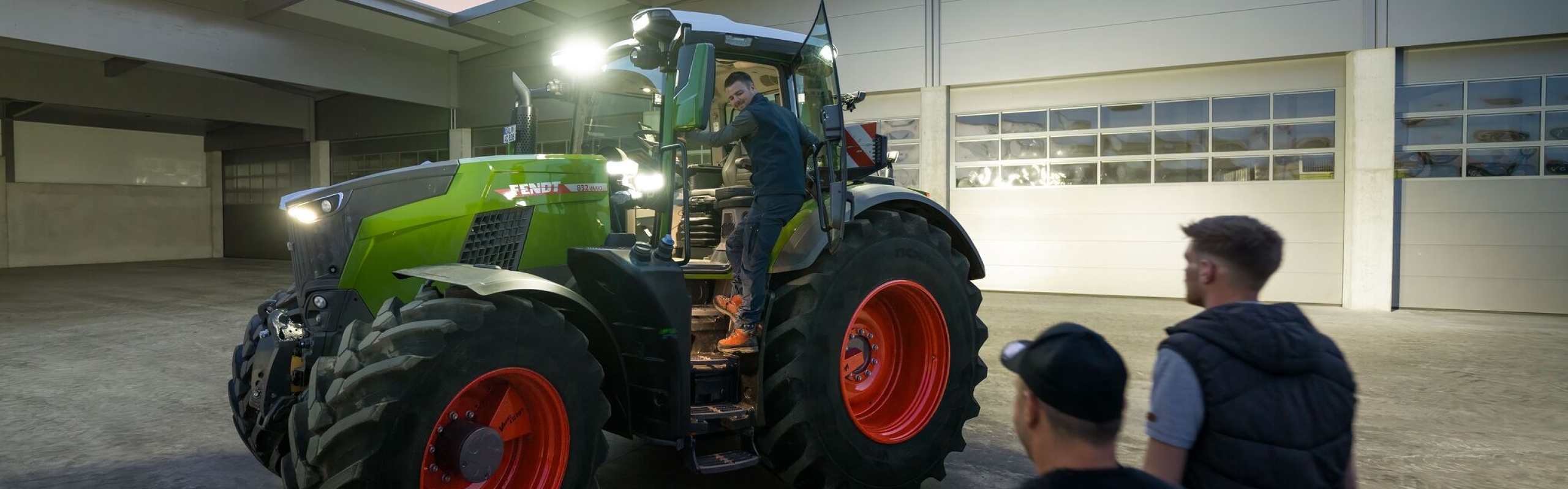 Zicht op de binnenplaats van een loonbedrijf dat voor de eigen rijders een Fendt 800 Vario klaar heeft staan, met alle verlichting aan