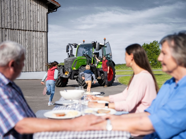 Campagnemotief voor de Fendt 300 Vario Op de boerderij zit het gezin aan de gedekte tafel, zichtbaar blij met de komst van de laatste twee gezinsleden: de boer met zijn Fendt 300 Vario