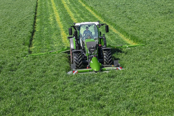 Bovenaanzicht op een groen veld met een Fendt-tractor tijdens het maaien